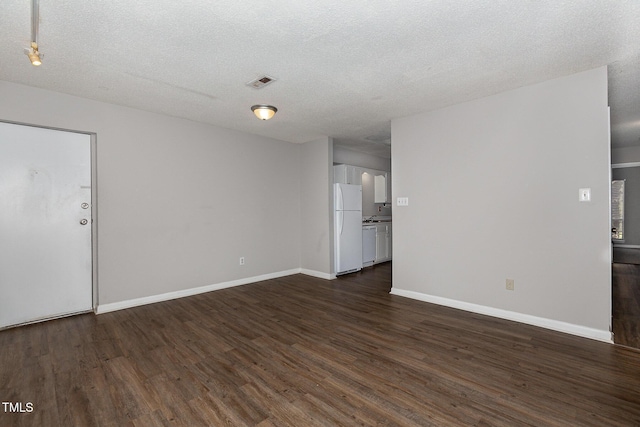 spare room with a textured ceiling and dark hardwood / wood-style floors