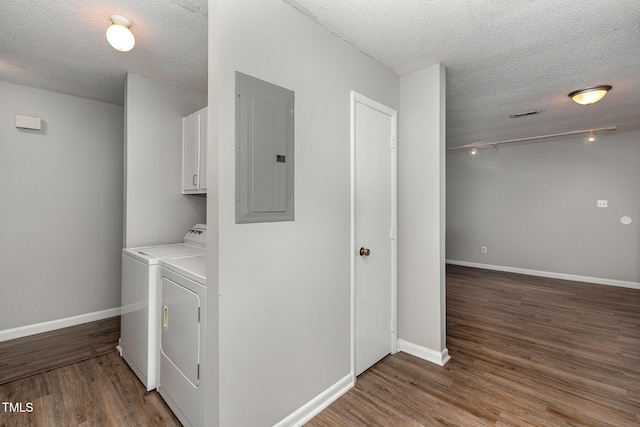 clothes washing area featuring a textured ceiling, electric panel, cabinets, separate washer and dryer, and dark hardwood / wood-style flooring