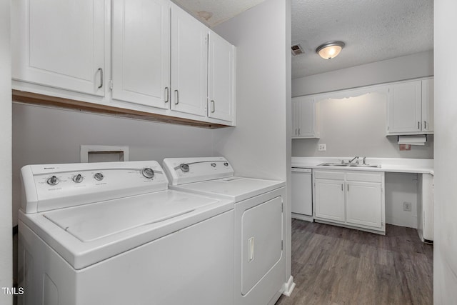 laundry area with washer and dryer, a textured ceiling, sink, and cabinets