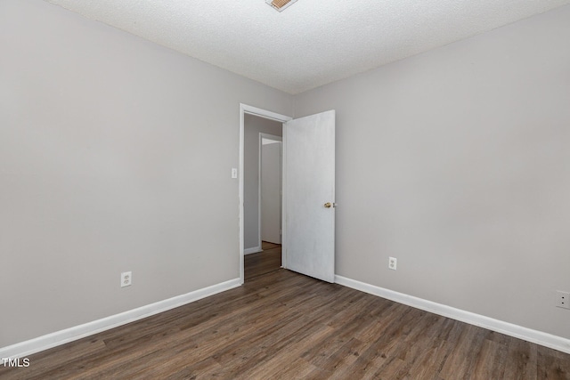 unfurnished room featuring a textured ceiling and dark hardwood / wood-style floors