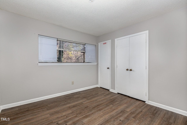 unfurnished bedroom with a textured ceiling, dark wood-type flooring, and a closet