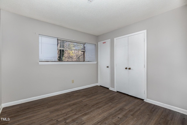 unfurnished bedroom with a closet, a textured ceiling, and dark hardwood / wood-style floors