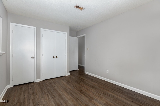 unfurnished bedroom with a textured ceiling and dark hardwood / wood-style floors