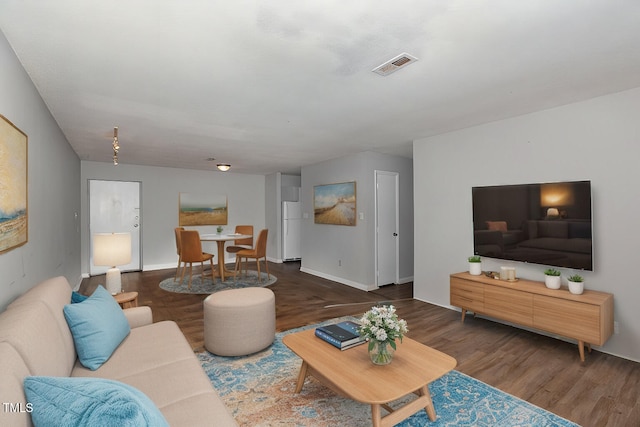 living area with dark wood-style floors, baseboards, and visible vents