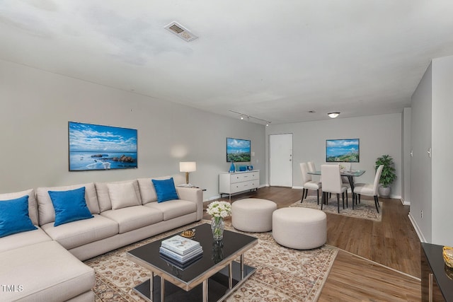 living room with baseboards, wood finished floors, visible vents, and track lighting