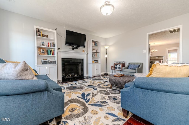 living room with a textured ceiling, built in features, and a notable chandelier