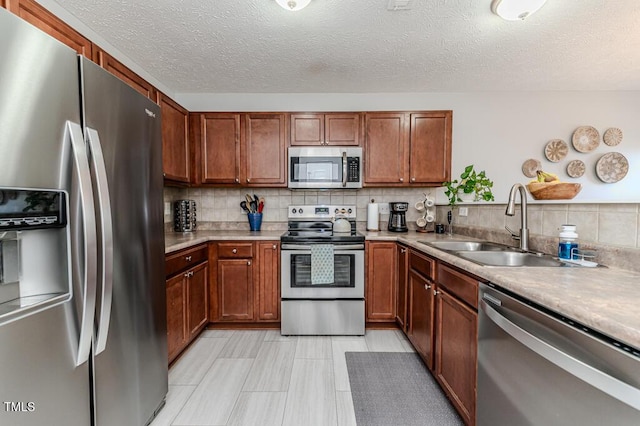 kitchen featuring decorative backsplash, sink, a textured ceiling, and appliances with stainless steel finishes