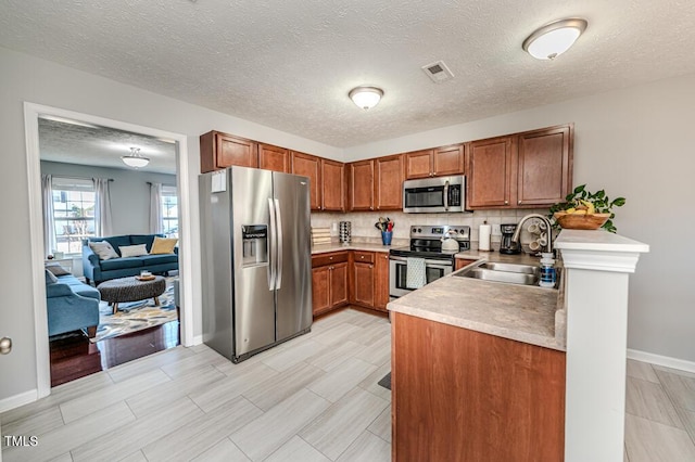 kitchen featuring sink, a textured ceiling, appliances with stainless steel finishes, and tasteful backsplash