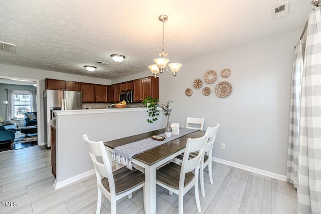 dining space with a textured ceiling and a notable chandelier