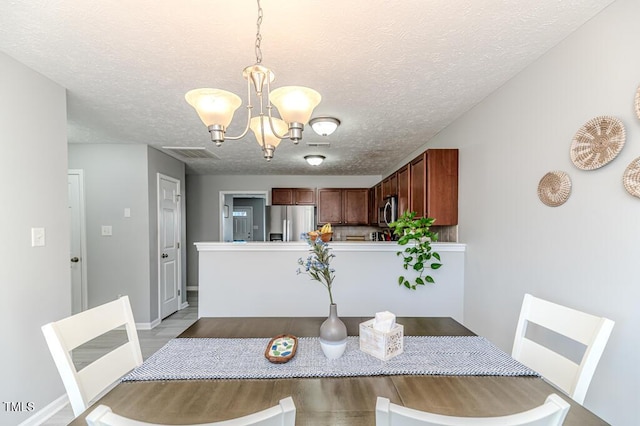 dining area with a textured ceiling, a chandelier, and light hardwood / wood-style flooring