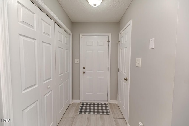 entryway with light wood-type flooring and a textured ceiling