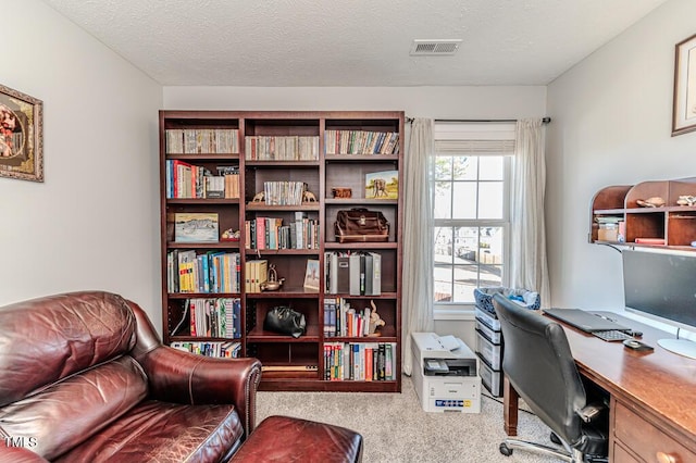 office space with a textured ceiling and light carpet