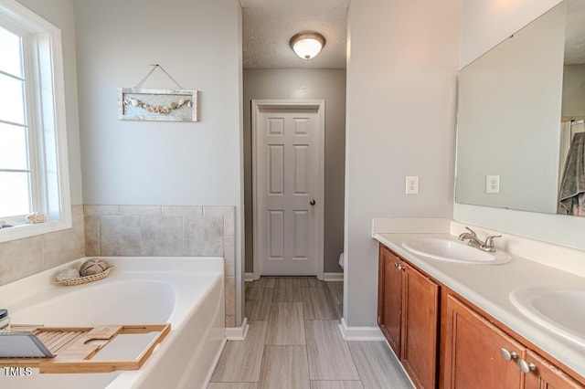 bathroom featuring vanity, a tub, a wealth of natural light, and a textured ceiling