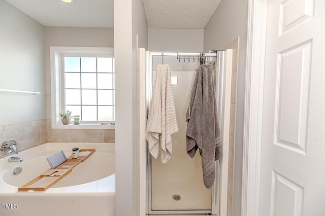 bathroom with a textured ceiling and shower with separate bathtub