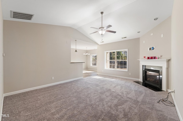 unfurnished living room with ceiling fan with notable chandelier, vaulted ceiling, and carpet flooring