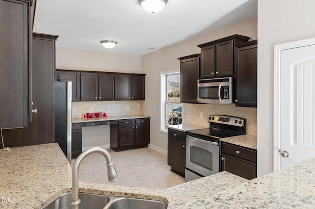 kitchen featuring stainless steel appliances, dark brown cabinetry, decorative backsplash, and sink