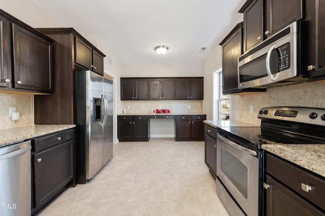 kitchen featuring light stone countertops, dark brown cabinetry, light tile patterned floors, and appliances with stainless steel finishes