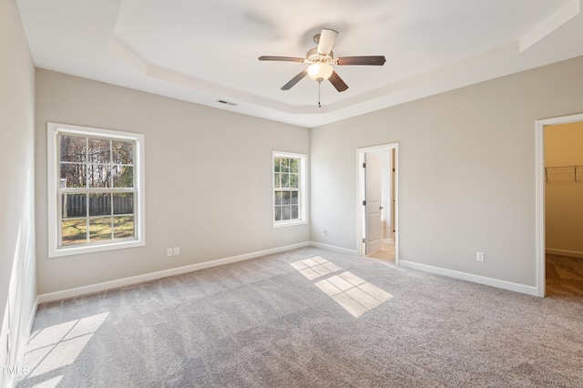 carpeted empty room with ceiling fan and a tray ceiling