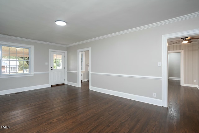 empty room with dark wood-type flooring, visible vents, ornamental molding, and baseboards