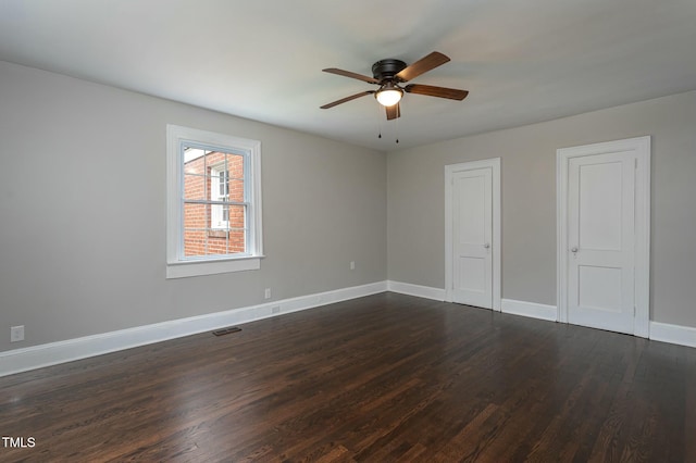 unfurnished bedroom with ceiling fan, dark wood-type flooring, visible vents, and baseboards