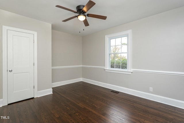 empty room with a ceiling fan, dark wood-style flooring, visible vents, and baseboards