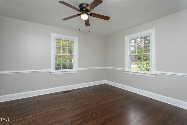 unfurnished room featuring dark wood-style floors, baseboards, visible vents, and ceiling fan