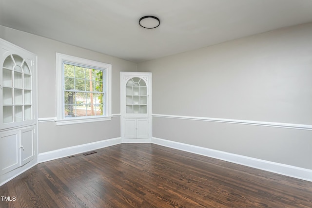 unfurnished room featuring visible vents, baseboards, and dark wood-style flooring