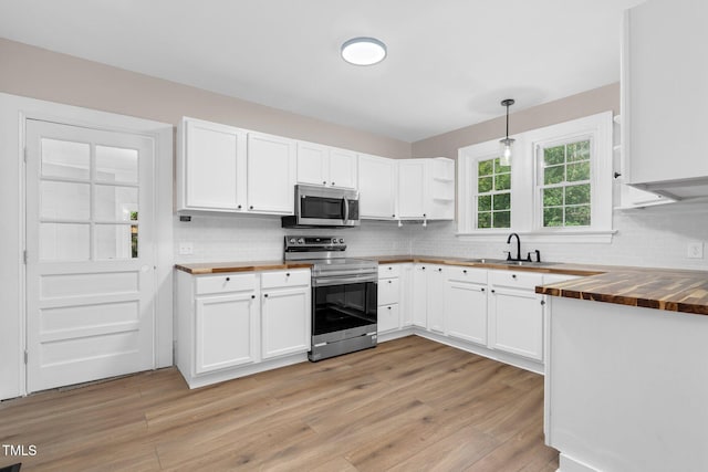 kitchen with butcher block counters, stainless steel appliances, a sink, and light wood-style flooring