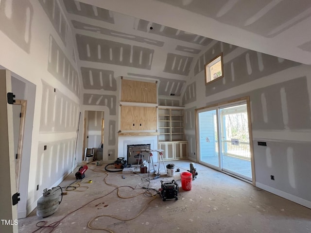 unfurnished living room featuring a towering ceiling and a fireplace