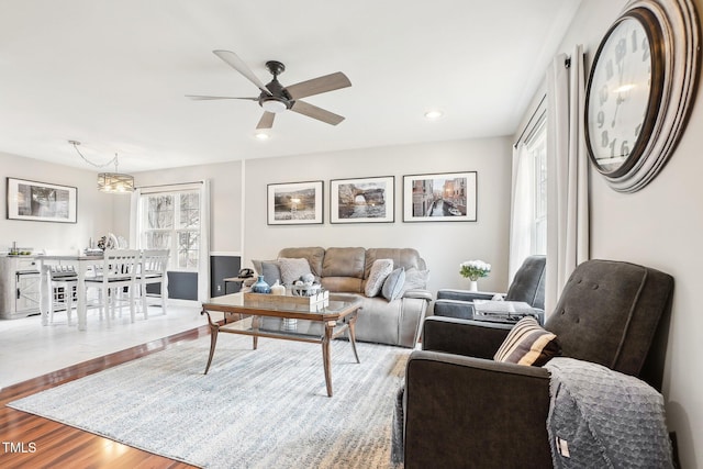 living room featuring ceiling fan with notable chandelier, a wealth of natural light, and light hardwood / wood-style floors