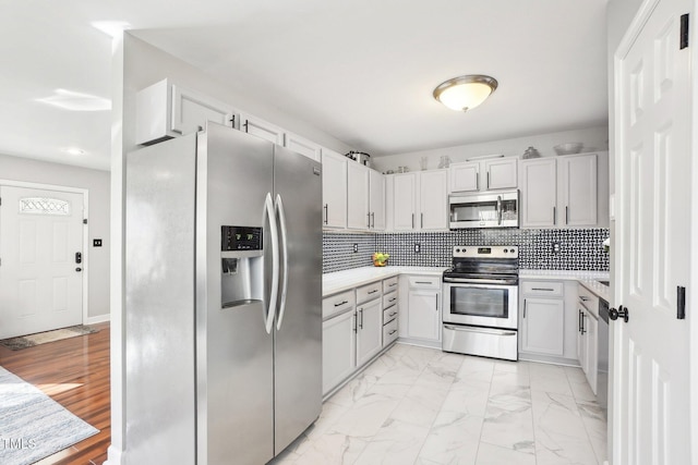 kitchen featuring tasteful backsplash, stainless steel appliances, and white cabinetry