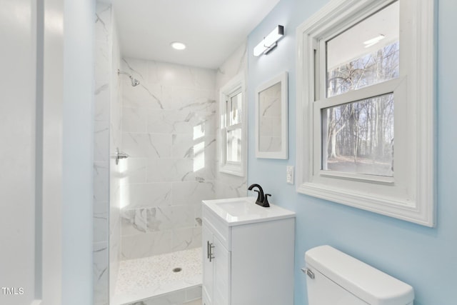 bathroom featuring vanity, tiled shower, and toilet