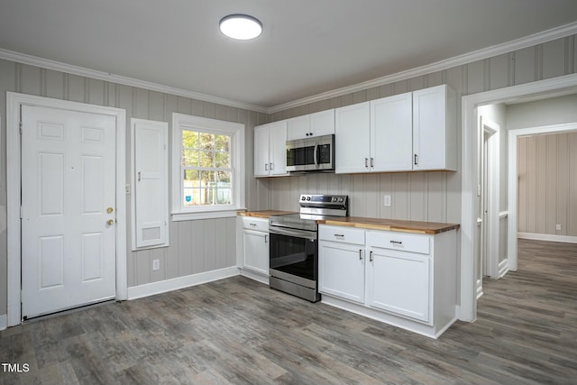 kitchen with appliances with stainless steel finishes, butcher block counters, white cabinetry, and ornamental molding