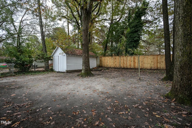 view of yard featuring a storage shed, a fenced backyard, and an outbuilding