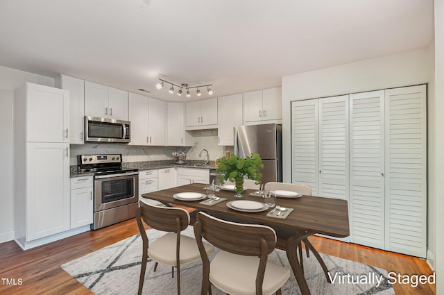 kitchen featuring sink, white cabinets, backsplash, stainless steel appliances, and dark wood-type flooring