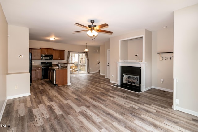 kitchen featuring dark wood-type flooring, sink, a center island, ceiling fan, and black appliances