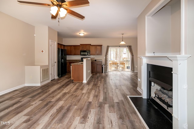 kitchen featuring a kitchen island, hardwood / wood-style floors, hanging light fixtures, ceiling fan, and black appliances