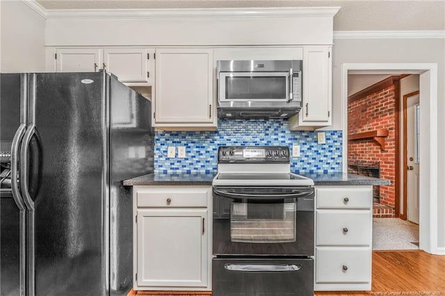 kitchen featuring white cabinets, black fridge, electric stove, and tasteful backsplash