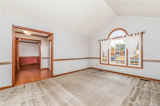 carpeted spare room featuring vaulted ceiling