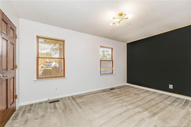 carpeted spare room with a notable chandelier