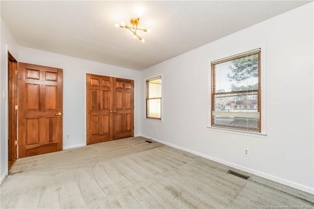 unfurnished bedroom with light carpet and a notable chandelier