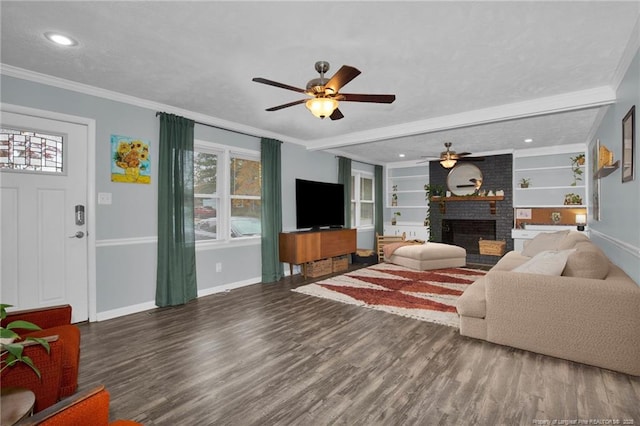 living room featuring ceiling fan, a fireplace, dark hardwood / wood-style floors, ornamental molding, and built in shelves