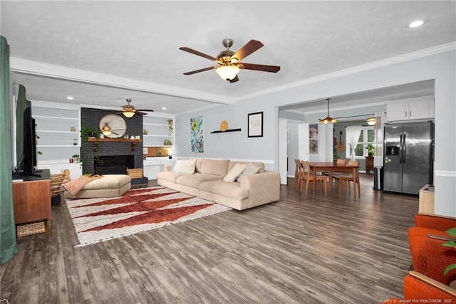 living room with ceiling fan, dark hardwood / wood-style floors, a fireplace, ornamental molding, and built in shelves