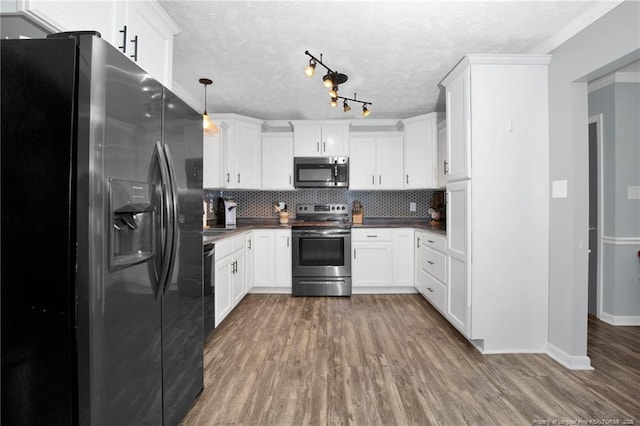 kitchen with hardwood / wood-style floors, decorative light fixtures, white cabinetry, stainless steel appliances, and tasteful backsplash