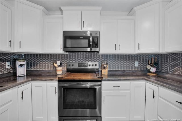 kitchen with decorative backsplash, ornamental molding, stainless steel appliances, and white cabinetry