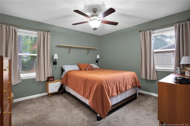 bedroom with ceiling fan, light colored carpet, and multiple windows