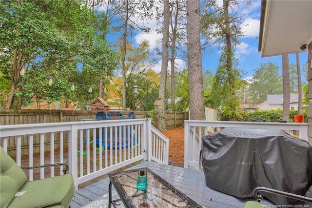 wooden terrace with a playground, a storage shed, and grilling area