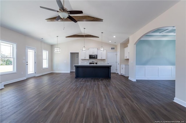 kitchen with white cabinets, decorative backsplash, hanging light fixtures, and an island with sink