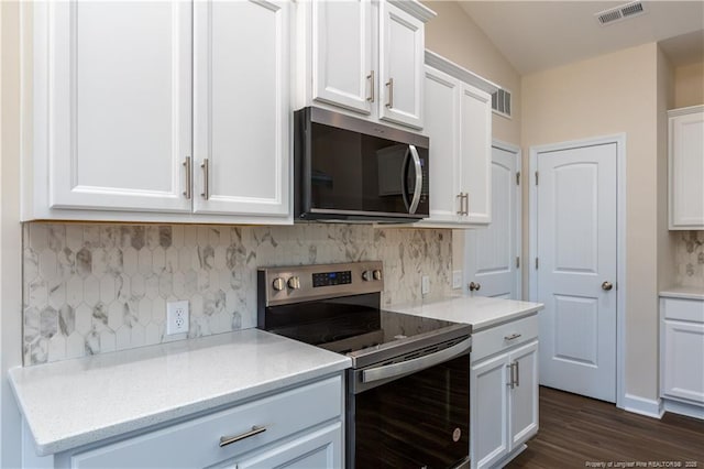 kitchen featuring appliances with stainless steel finishes, vaulted ceiling, backsplash, and white cabinetry