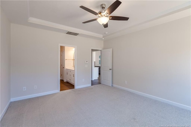 unfurnished bedroom with ceiling fan, ensuite bathroom, a raised ceiling, and carpet